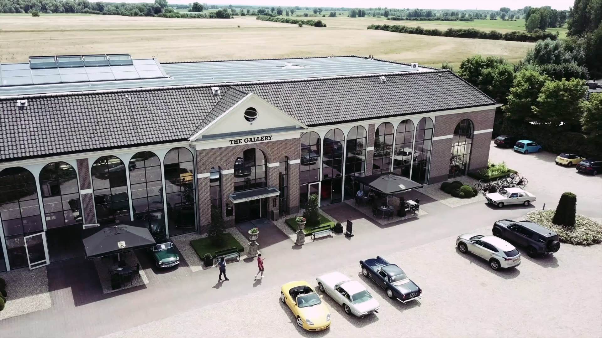 The Gallery Aaldering showroom seen from the air, classic cars on the forecourt.